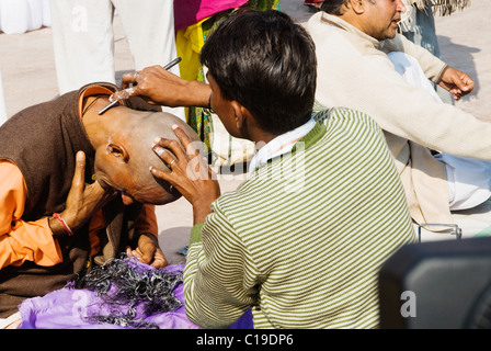 Barbier rasieren des Kopfes eines Pilgers, Haridwar, Uttarakhand, Indien Stockfoto