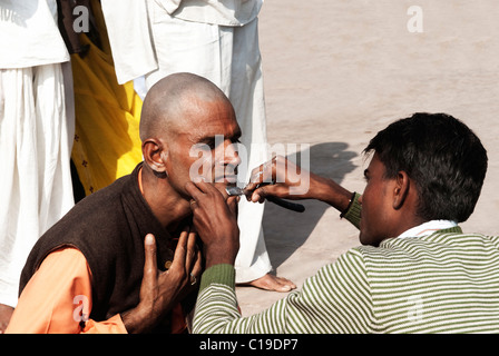 Barbier rasieren der Kopf und das Gesicht eines Pilgers, Haridwar, Uttarakhand, Indien Stockfoto