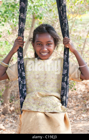 Glückliches armes niedrigeres Kaste indischen Straße Mädchen lächelnd saß in einem Sari-Schwung. Andhra Pradesh, Indien Stockfoto