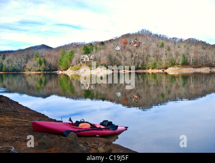 Eine rote Kajak hochgezogen am Ufer im Winter. Stockfoto