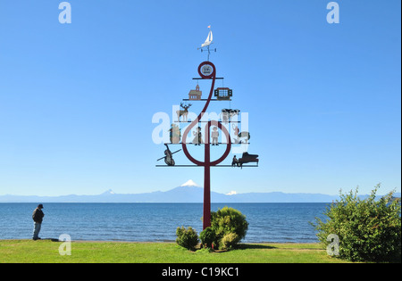 Blauer Himmelsansicht des Menschen durch ein Musikfestival Schild an einer grünen See Llanquihue Uferpromenade in Richtung Volcan Osorno, Frutillar, Chile Stockfoto