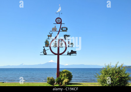 Blauer Himmel mit Blick auf eine hoch Musikfestival Hinweis Schriftzug auf einer grünen See Llanquihue Uferpromenade in Richtung Volcan Osorno, Frutillar, Chile Stockfoto