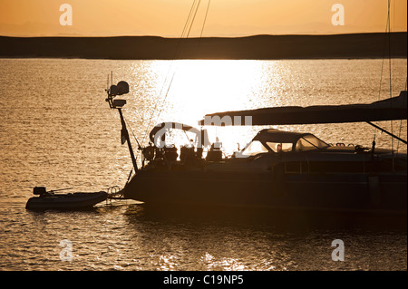 Private Segelyacht, die Silhouette bei Sonnenuntergang während vor Anker Stockfoto