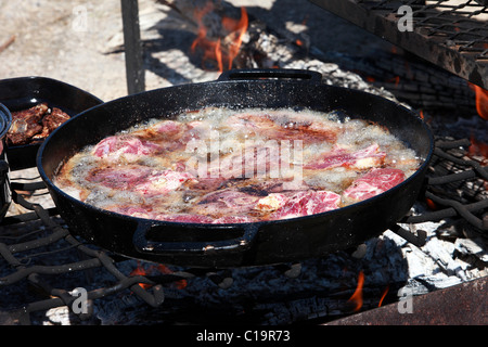 Lammkotelett Steaks und Hammelfleisch Kochen in Gusseisen Pfannen über dem offenen Feuer im Freien. Cowboy und Schafe Camp Bbq und Party. Stockfoto