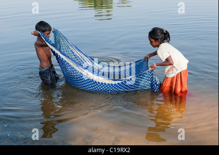 Armen indischen niedrigere Kaste Kinder fangen Fische mit einem Sari im Fluss. Andhra Pradesh, Indien Stockfoto