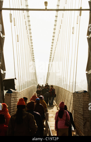 Touristen zu Fuß auf einer Hängebrücke Lakshman Jhula, Fluss Ganges, Rishikesh, Uttarakhand, Indien Stockfoto