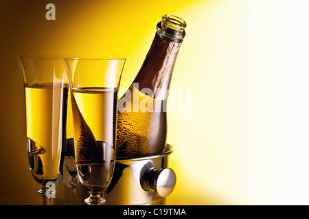 Flasche Champagner im Kühler und zwei Sektgläsern. Auf einem gelben isoliert. Stockfoto