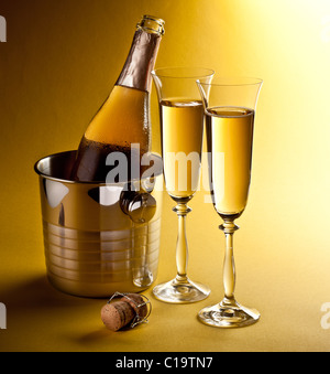 Flasche Champagner im Kühler und zwei Sektgläsern. Auf einem gelben isoliert. Stockfoto