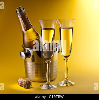 Flasche Champagner im Kühler und zwei Sektgläsern. Auf einem gelben isoliert. Stockfoto