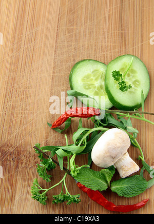 Knoblauch, Pilze, Paprika, Petersilie, Gurke und Gewürze auf einem Schneidebrett Stockfoto