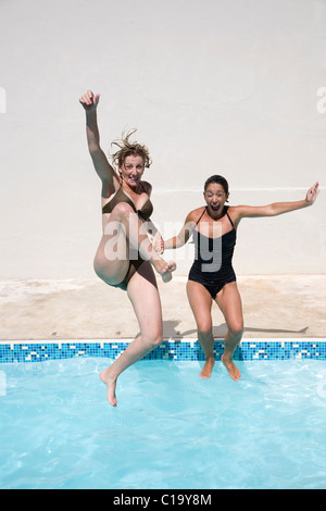 Zwei applying Freunden ins Schwimmbad springen und Spaß Stockfoto