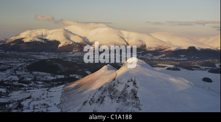 Am späten Abend Winter Sonnenlicht auf Schnee bedeckten Catbells und Skiddaw im englischen Lake District Stockfoto