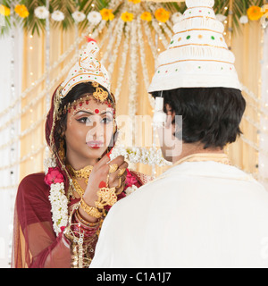 Durchführung von Mala Badal (Austausch von Garland) Zeremonie in Bengali Hochzeit paar Stockfoto