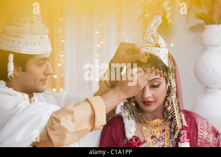 Durchführung Sindoor Daan Zeremonie in Bengali Hochzeit paar Stockfoto