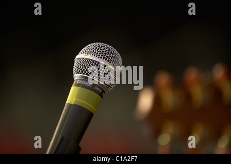 Shure sm58 Mikrofon auf einem Ständer bei einem Auftritt mit Gitarre Kopf im Vordergrund unscharf Stockfoto