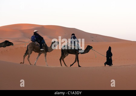 Touristen auf einem Kamel camping-Ausflug bei Sonnenaufgang in der Sahara Wüste, Erg Chebbi, Marokko. Stockfoto