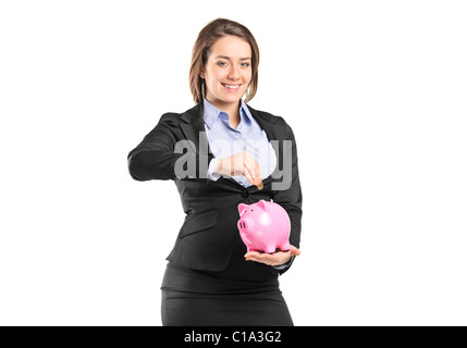 Eine Geschäftsfrau, eine Münze in ein Sparschwein Stockfoto