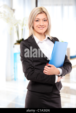 Glücklich Geschäftsfrau mit blauen Ordner posiert im Büro Stockfoto