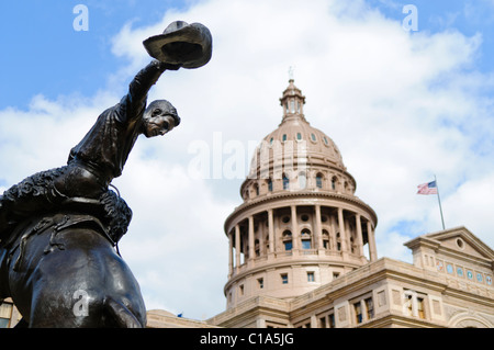 AUSTIN, Texas, USA — im Vordergrund steht eine Bronzestatue eines Cowboys auf einem Pferd auf dem Gelände des Texas State Capitol in Austin. Der Künstler war Constance Whitney Warren und wurde am 17. Januar 1925 enthüllt. Das Gebäude wurde im Stil der italienischen Renaissance erbaut. Stockfoto