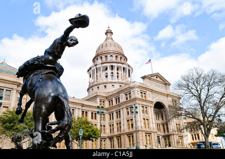 AUSTIN, Texas - Im Vordergrund steht eine Bronzestatue von ein Cowboy auf einem Pferd auf dem Gelände der Texas State Capitol in Austin. Der Künstler war Konstanz Whitney Warren und es war am 17. Januar 1925 vorgestellt. Das Gebäude ist im Stil der italienischen Renaissance Revival gebaut. Stockfoto