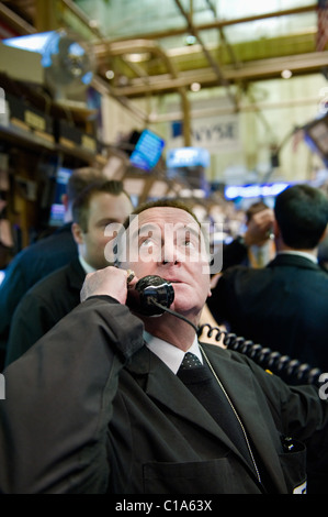 Ein Effektenhändler schaut ängstlich auf den Bildschirmen um ihn herum und ruft in einer Reihenfolge. Stockfoto