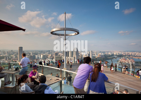 Besucher blicken auf die Skyline von Singapur von der Aussichtsplattform des Marina Bay Sands SkyPark.  Marina Bay, Singapur Stockfoto
