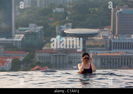 Frau, Schwimmen im Pool im Marina Bay Sands SkyPark mit Skyline der Stadt im Hintergrund.  Marina Bay, Singapur Stockfoto