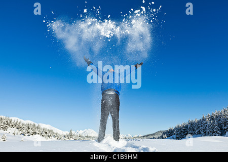 Ein männlicher Wanderer auf Schneeschuhen in Alaska wirft Schnee in der Luft mit dem Ausdruck ihrer Freude am sonnigen Tag und Berglandschaft. Stockfoto