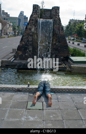 Ein Obdachloser badet in einem öffentlichen Brunnen in der Mitte von Chapultepec Avenue in der Innenstadt von Mexiko-Stadt. Stockfoto
