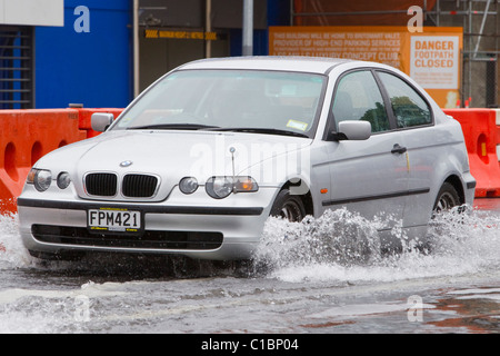 Ein Auto fährt durch Wasser auf einer überfluteten Straße Stockfoto