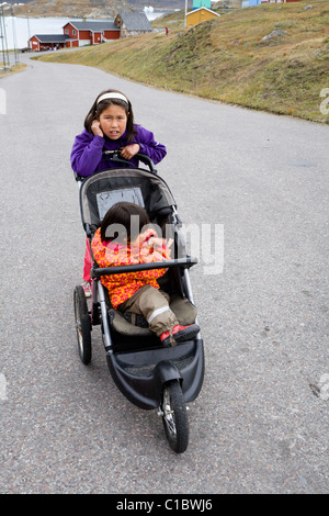 Mädchen treibt ein Baby Kinderwagen, Narsaq, Süd-Grönland. Stockfoto