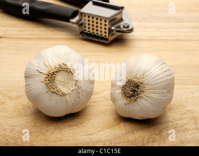 Knoblauch pressen und zwei Knoblauchzehen Stockfoto