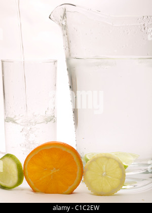 Scheibe der Zitrone, Limette und Orange mit einem Glas mit Wasser gegossen wird und einen Krug Stockfoto