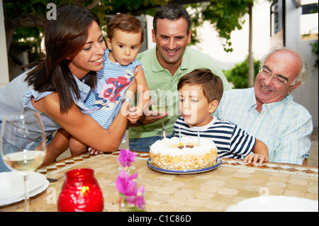Familie bläst die Kerzen aus auf Kuchen Stockfoto