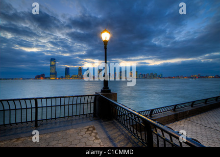 Promenade an der World Financial Center Boat Basin in Manhattan in der Nacht mit Jersey City sichtbar auf dem gegenüberliegenden Ufer Stockfoto