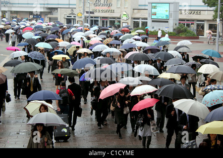 Eine Schar von Pendlern verlassen den Hauptbahnhof in Yokohama Japan im Regen tragen Regenschirme Stockfoto