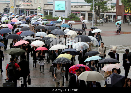 Eine Schar von Pendlern verlassen den Hauptbahnhof in Yokohama Japan im Regen tragen Regenschirme Stockfoto