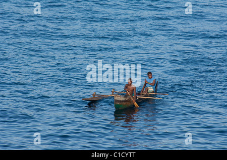 Madagaskar, Indischer Ozean, vor der Küste von der Insel von Nosy Be. Madagassischer Männer in hölzernen Auslegerkanu. Stockfoto