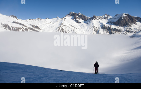 Ein Mann klettert einen schneebedeckten Berghang mit Klettern Skins auf seinen Skiern am Col du Lautaret, in der Nähe von La Grave, Frankreich. Stockfoto