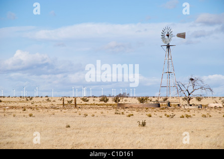 Eine alte Windmühle knarrt im Wind wie Windräder in der Ferne Strom erzeugen. Stockfoto