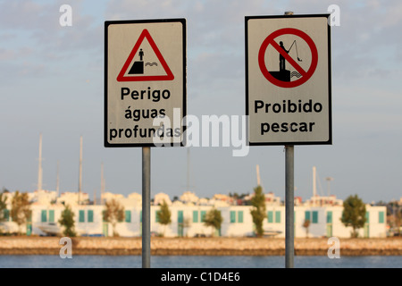 Warnung vor Zeichen "Keine Fischerei" und "Gefahr Tiefenwasser" an der Küste von Portimao, Algarve, PORTUGAL. Weiße Häuschen sind sichtbar Stockfoto