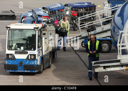 Die Mitarbeiter des Flughafens bringt einen Koffer auf einem Förderband-Band. Finnair. Flughafen Helsinki, Vantaa, Finnland Stockfoto