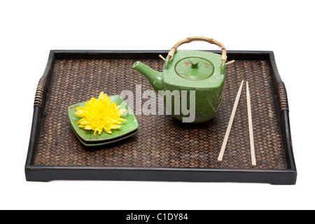 Bambus-Tablett, grüne Keramik Teekanne, Untertasse, gelbe Chrysantheme und Ess-Stäbchen auf weißem Hintergrund Stockfoto