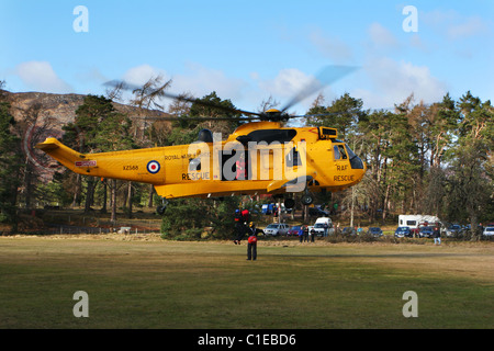 RAF Sea King SAR Hubschrauber schwebt und Windenbetrieb Mitglied Aviemore Mountain Rescue Team an Bord bei Rothiemurchus in der Nähe von Aviemor Stockfoto