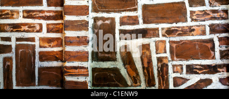 Wand aus braunen Steinen kreativ angeordnet. Stockfoto