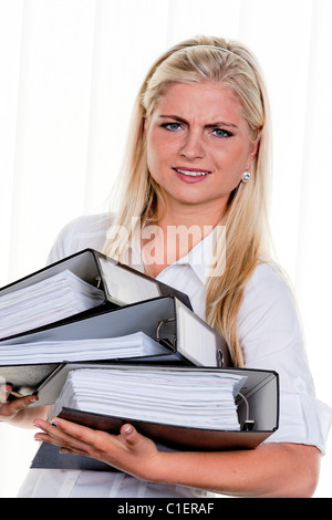 junge Frau mit Haufen Arbeit Stockfoto