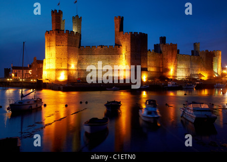 Caernarfon Castle wider in River Seiont, in der Abenddämmerung, Caernarfon, Wales, Vereinigtes Königreich Stockfoto