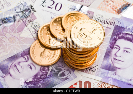 Ein Stapel von Krügerrand auf Pfund-Noten Stockfoto