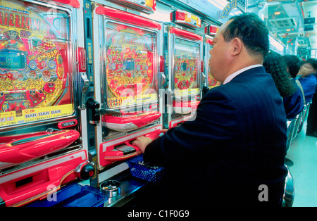 Japan, Tokyo, Mann spielen Pachinko in eine Spielhalle Stockfoto