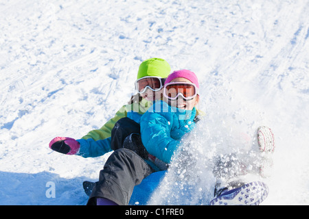 Gemischte Rassen Mädchen im Schnee Rodeln Stockfoto